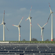 Wind turbines and solar panels sit in a field.